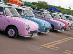 a row of colorful cars parked next to each other on top of a parking lot