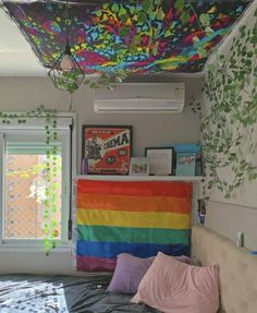 a bed with a rainbow blanket hanging from the ceiling