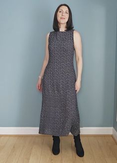 a woman standing in front of a blue wall wearing a black and white patterned dress