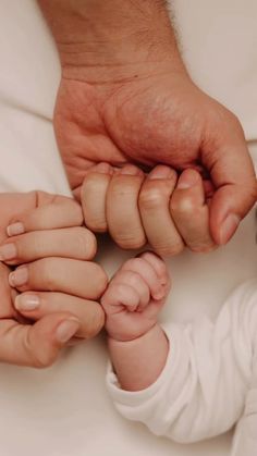 a close up of a person holding a baby's hand with the other hand