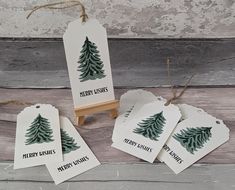 christmas tree tags with merry wishes written on them hanging from clothes pins and wooden stand