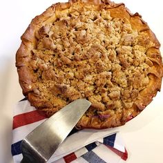 a pie sitting on top of a white table next to a knife and napkin with an american flag design