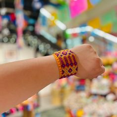 a woman's arm with a bracelet on it in front of a store display