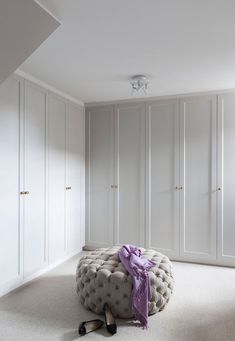 a bedroom with white closets and a round foot stool in the middle of the room