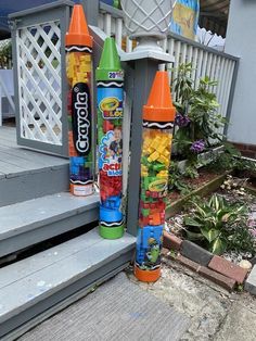 two plastic crayons are sitting on the steps next to each other in front of a house