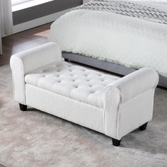 a bed with a white and gray upholstered bench in front of the bed