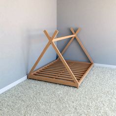 a wooden bed frame sitting on top of carpeted floor next to a gray wall