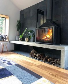 a living room with a fire place in the center and wood logs on the floor