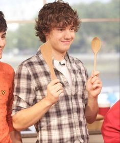 two young men standing next to each other holding wooden spoons