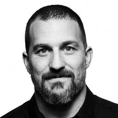 a black and white photo of a man with a goatee on his head looking at the camera