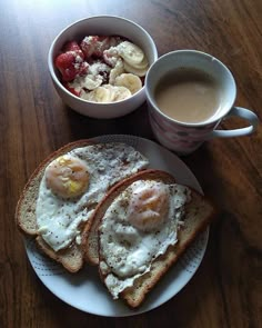 two eggs and toast on a plate next to a cup of coffee with strawberries