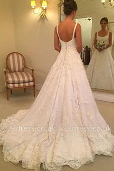 a woman standing in front of a mirror wearing a wedding dress