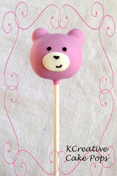 a pink bear lollipop sitting on top of a wooden stick