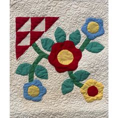 a quilted wall hanging with colorful flowers on it's sides and an arrow