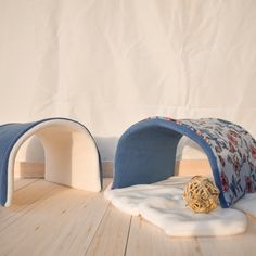 a cat bed with a ball on the floor next to it and a white wall in the background