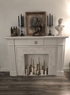 a white fireplace with candles and pictures on the mantle