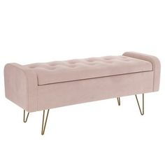 an upholstered bench with gold legs and a light pink velvet cover on it