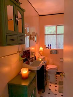 a bathroom with a sink, toilet and candles on the counter in front of it