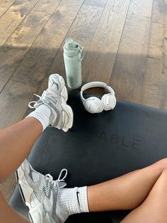 a woman sitting on top of a yoga mat next to a cup and headphones