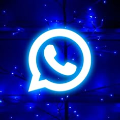 whatsapp logo lit up in the dark with blue lights around it and tree branches