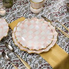 the table is set with pink and white dishes, silverware, and napkins