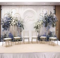 a stage set up for a wedding with chairs and flowers on the back drop cloth