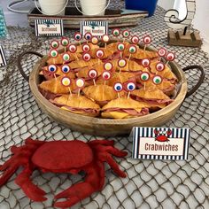 crab cakes are arranged in a wooden bowl on a table with place cards and decorations