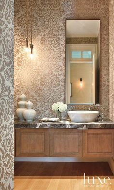 a bathroom with two sinks and a large mirror above the sink is decorated in damask wallpaper