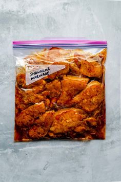 a bag filled with chicken wings sitting on top of a cement floor next to a wall