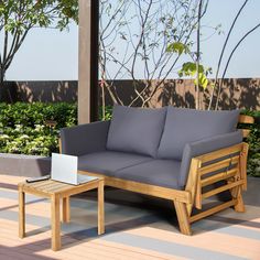 a couch sitting on top of a wooden floor next to a table with a laptop