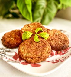 three fried food items on a plate with sauce and green leafy greens in the background