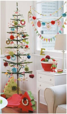 a decorated christmas tree in the corner of a living room with other decorations on the wall