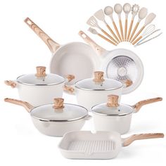 a group of white pots and pans with wooden spoons next to each other