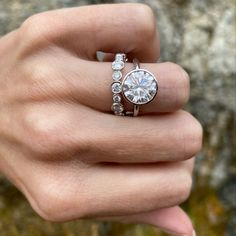 a woman's hand holding an engagement ring with two diamonds on the top and bottom