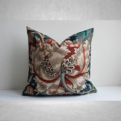 a decorative pillow sitting on top of a white table next to a gray and blue wall