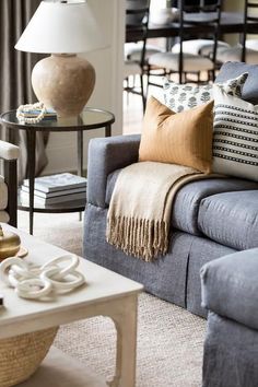 a living room filled with lots of furniture and pillows on top of a couch next to a coffee table