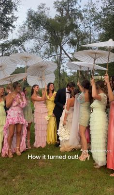 a group of people standing around each other holding umbrellas in the grass with trees in the background