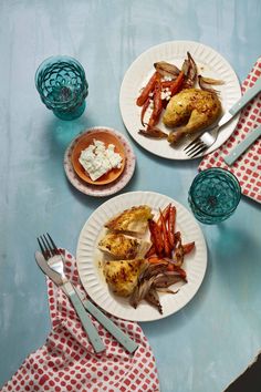 two white plates topped with chicken, carrots and potatoes on top of a blue table