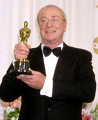 an older man in a tuxedo holding up his oscar statue