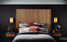 a bedroom with black walls and wooden headboard on the wall, along with two nightstands