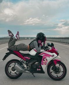 a person laying on top of a pink and white motorbike in the middle of an empty highway