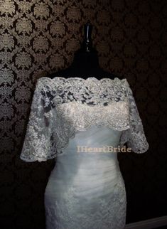 a white wedding dress on a mannequin in front of a wallpapered background