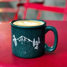 a green coffee cup sitting on top of a red table