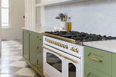 a green and white kitchen with an oven, stove top and checkered flooring