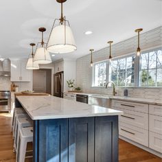 a large kitchen with an island in the middle and two pendant lights hanging from the ceiling