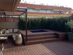 an outdoor hot tub sitting on top of a wooden deck next to a couch and table