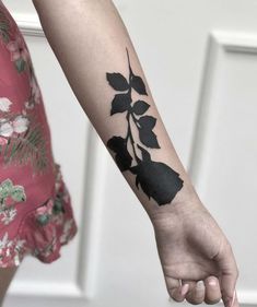 a woman's arm with a black flower tattoo on it