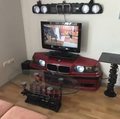 a flat screen tv sitting on top of a glass table in front of a red couch