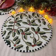 a table topped with a christmas themed placemat next to a plate and potted plant