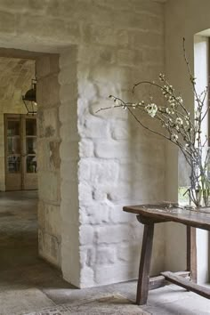 a vase with flowers sitting on top of a wooden table in front of a window